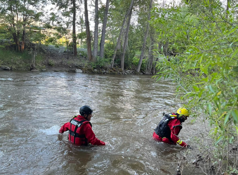 Two people in Central Okanagan Search and Rescue members walking through a creek.